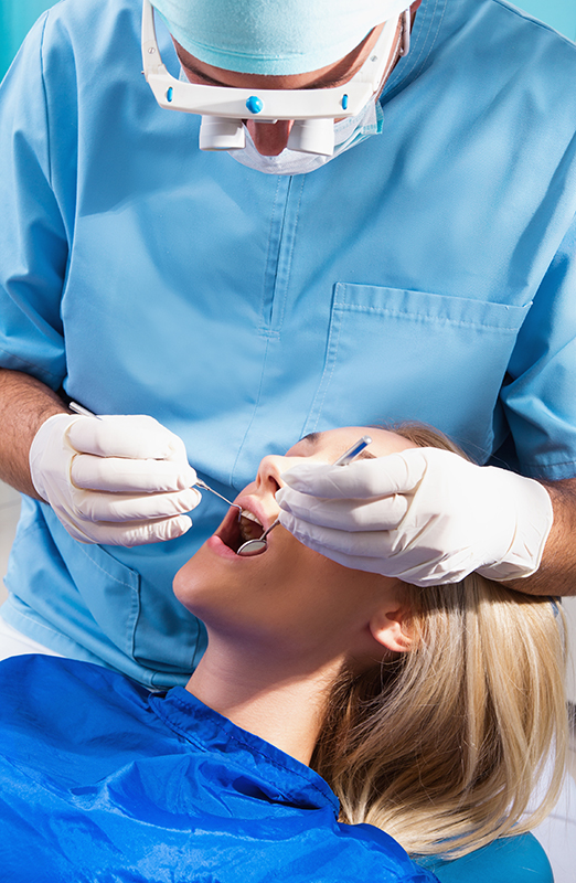 Image of a dental professional checking a woman patient's mouth.